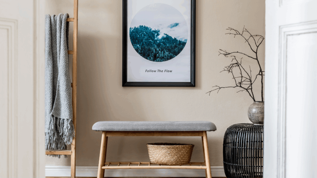 Minimalistyczne wnętrze z ławką z jasnego drewna, dekoracyjnym plakatem i plecionym koszem.
