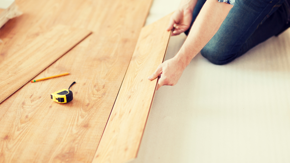 Osoba montująca panele podłogowe w jasnym odcieniu drewna