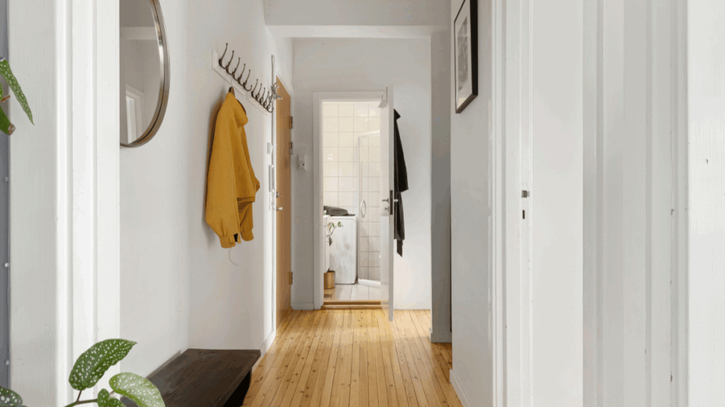 mały wąski przedpokój z jasnymi ścianami i drewnianą podłogą
