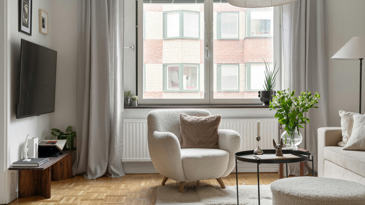 Przytulny salon z dużym oknem i zasłonami pokazujący skuteczne wyciszenie pokoju