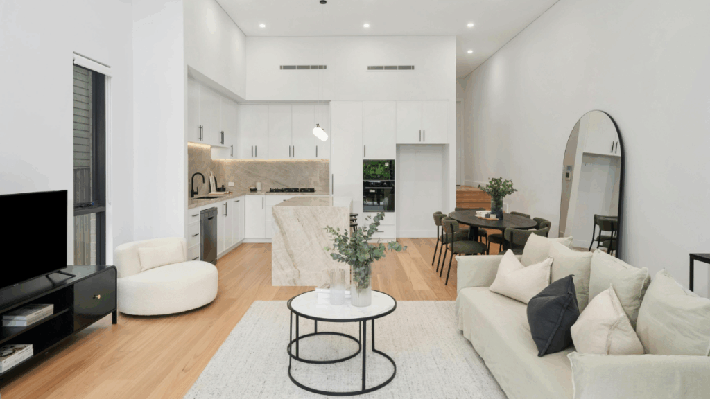 Salon z aneksem kuchennym w jasnych barwach z wyspą i lustrem